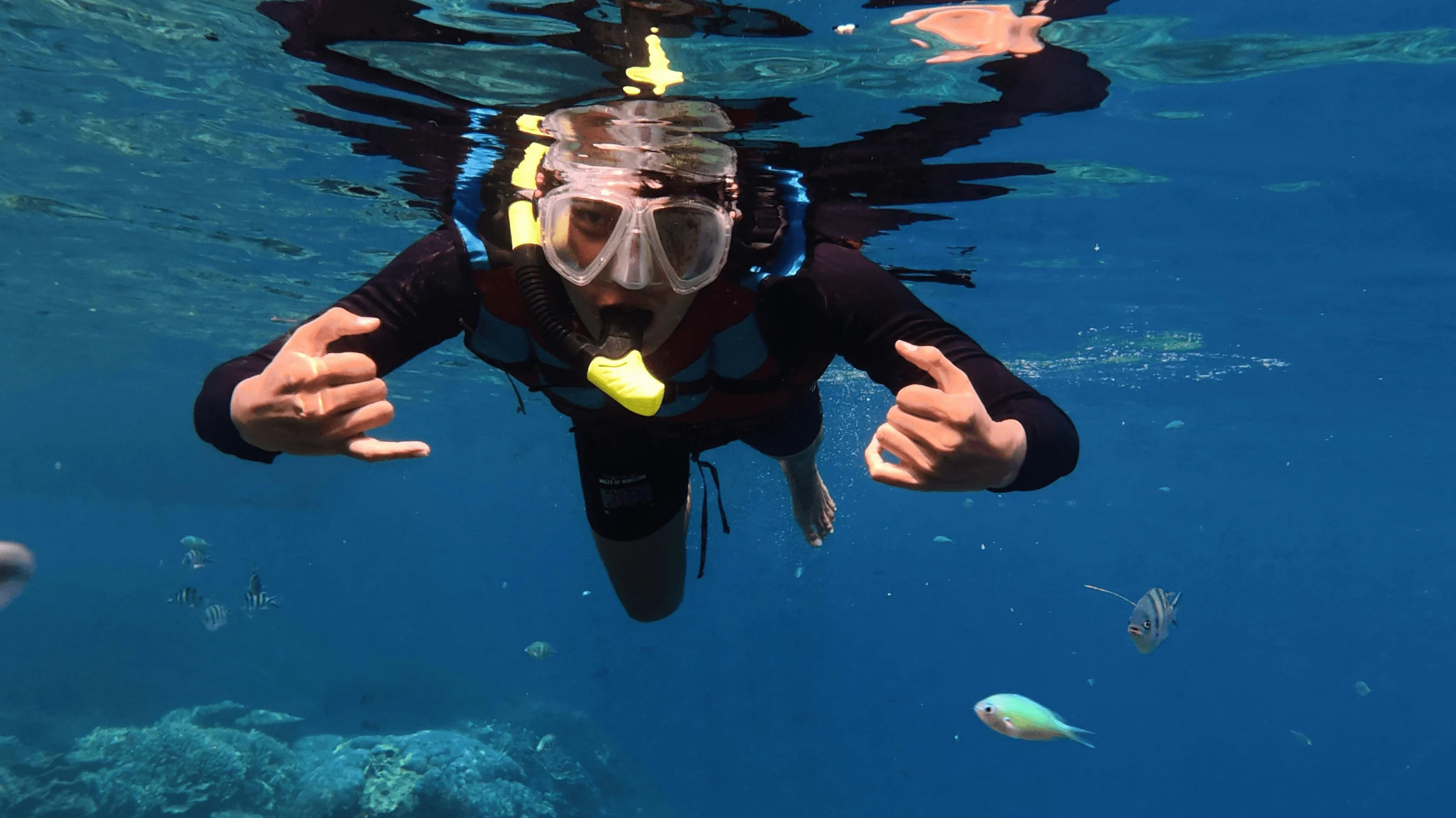 A free diver underwater, giving a shaka sign